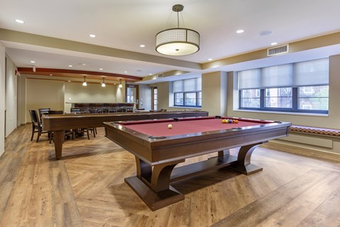A pool table is in the middle of a room with wood floors.